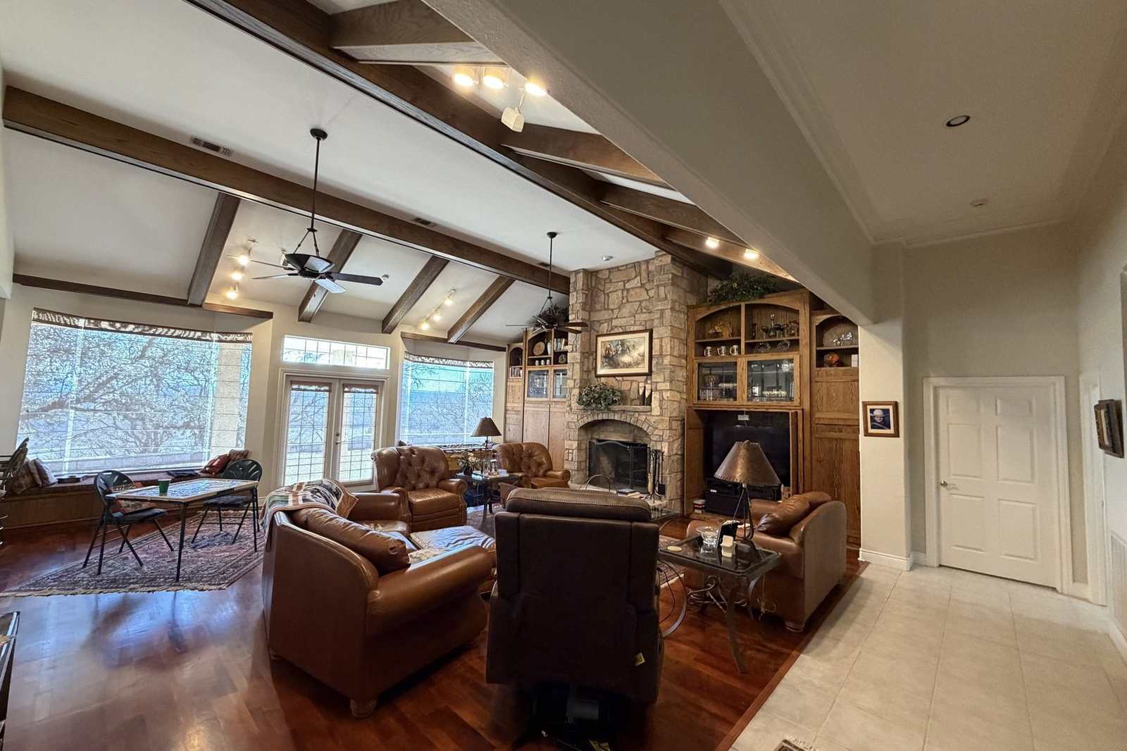 Great room of the ranch lodge — vaulted beams, leather seating and a stone fireplace